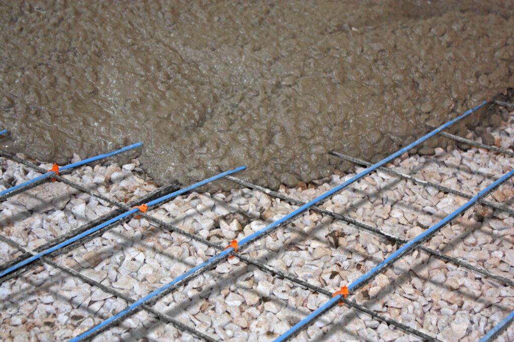 photo of wet concrete being poured onto rebar and floor heating elements