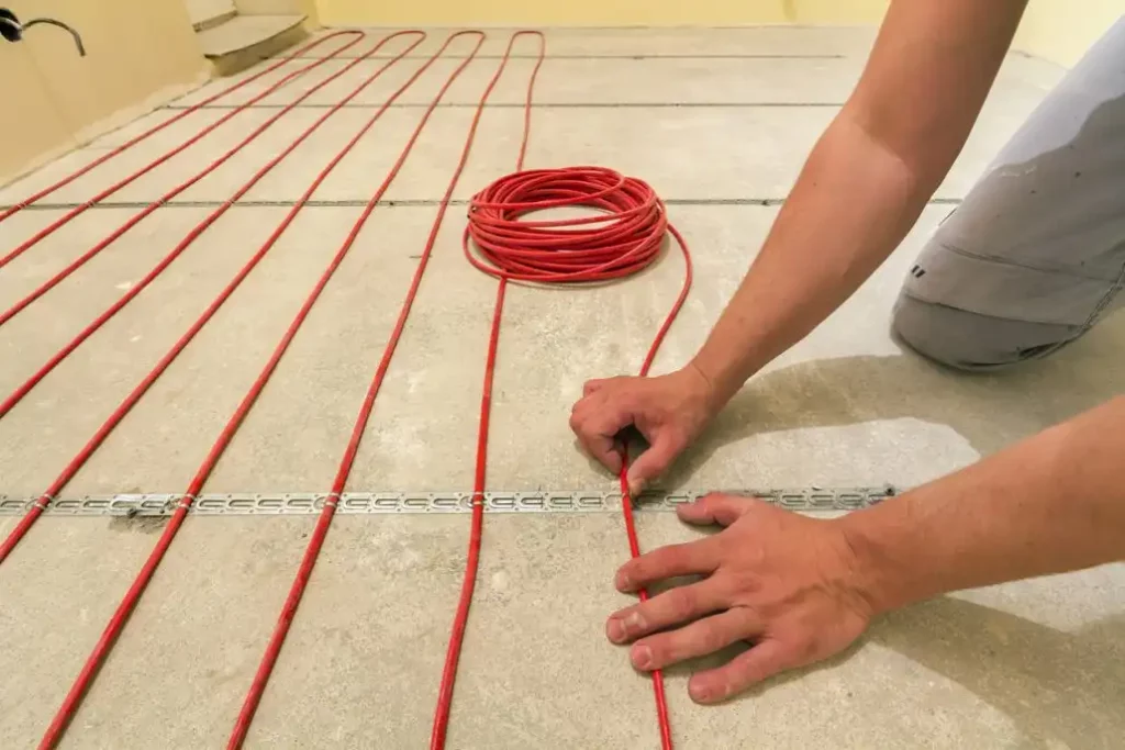 photo of man laying heating elements on base layer of floor