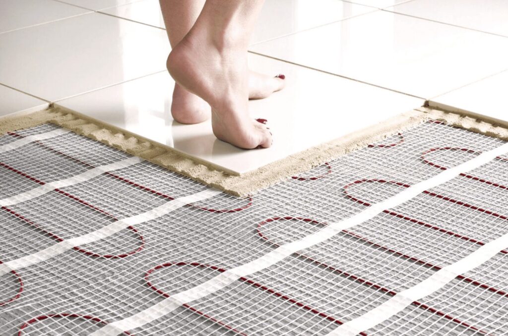 picture showing woman's feet on tiles with under floor heating revealed by cutaway